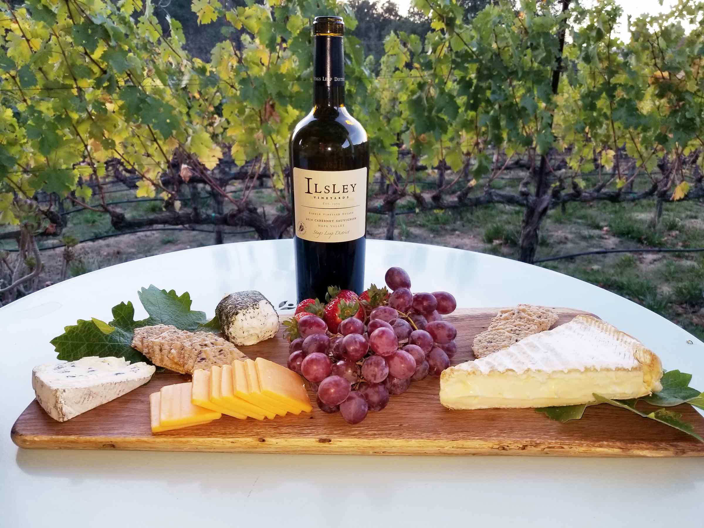 charcuterie board and bottle of Ilsley wine, overlooking a green vineyard